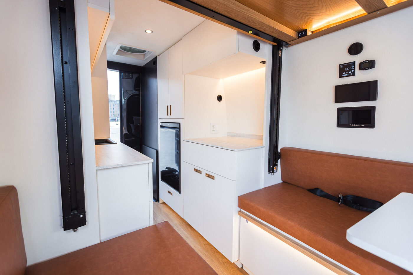 Galley and workstation layout inside a custom van build, appliances and monitors integrated