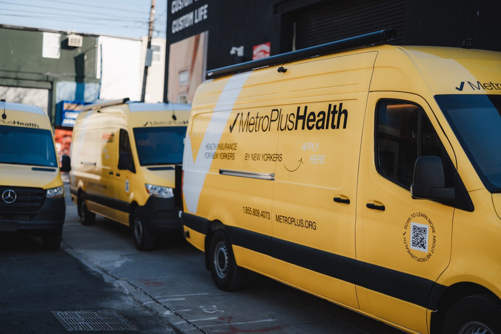 MetroPlusHealth branded mobile enrollment Sprinter fleet on a Brooklyn street